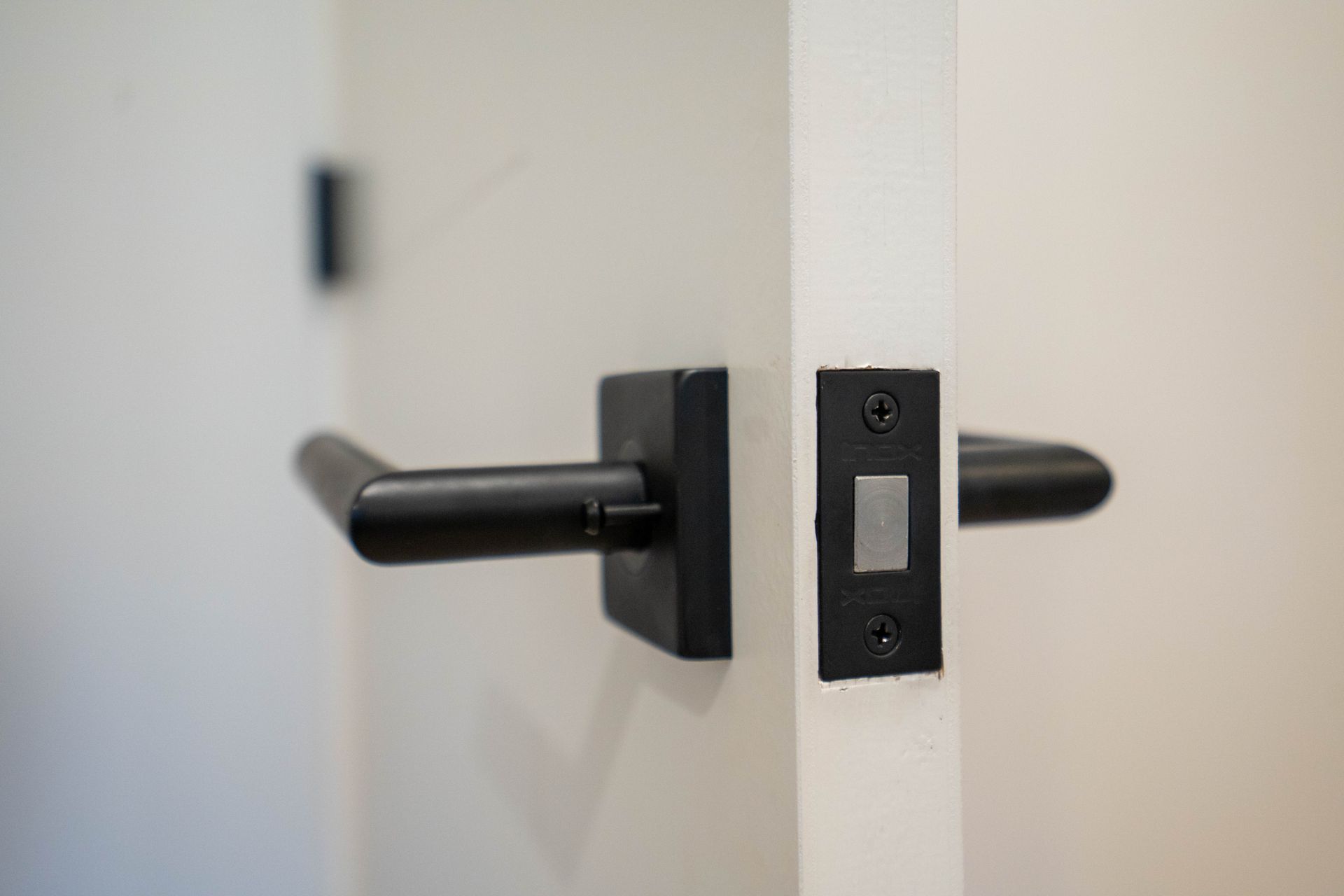 A close up of a black door handle on a white door.