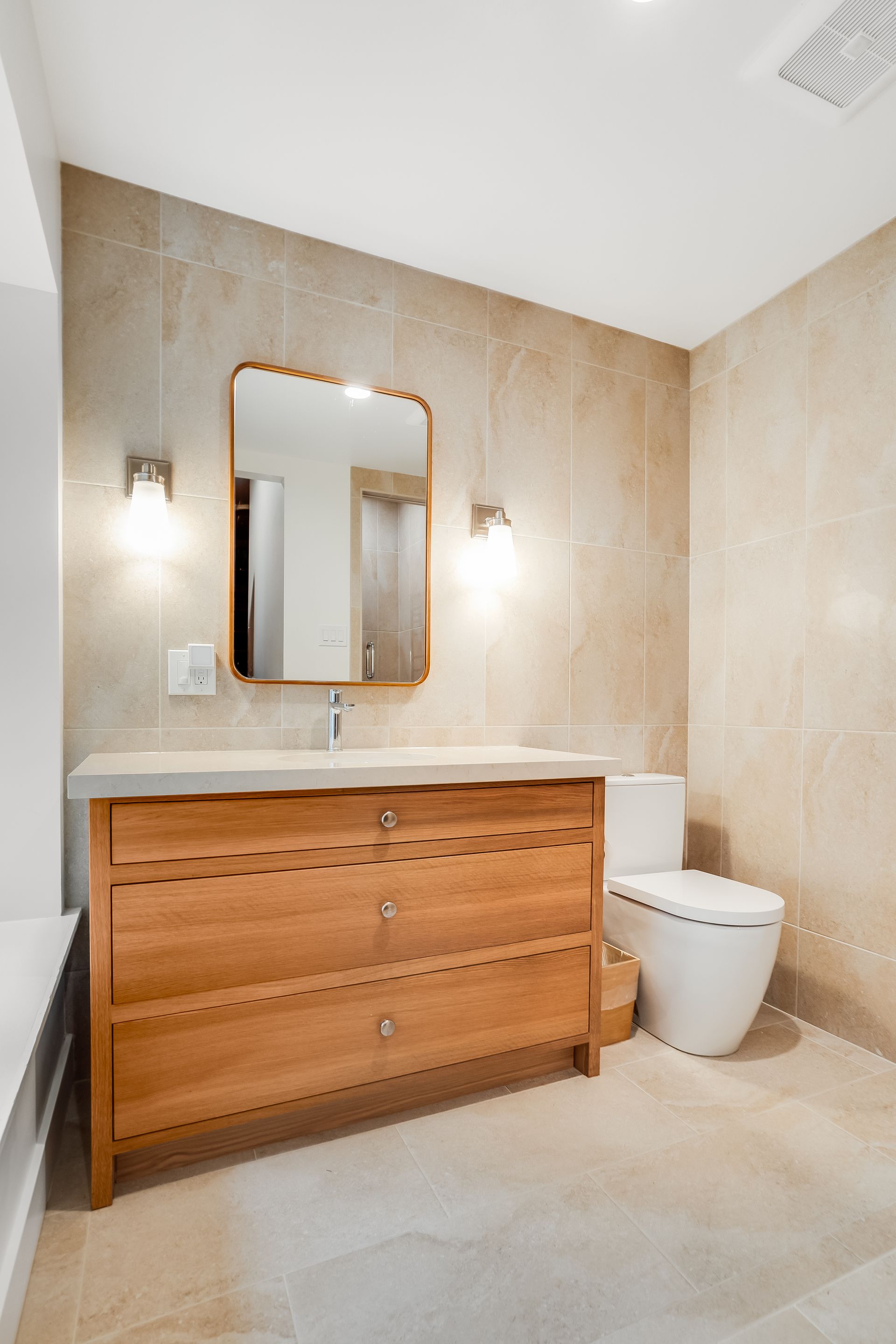 A bathroom with a sink , toilet , mirror and dresser.