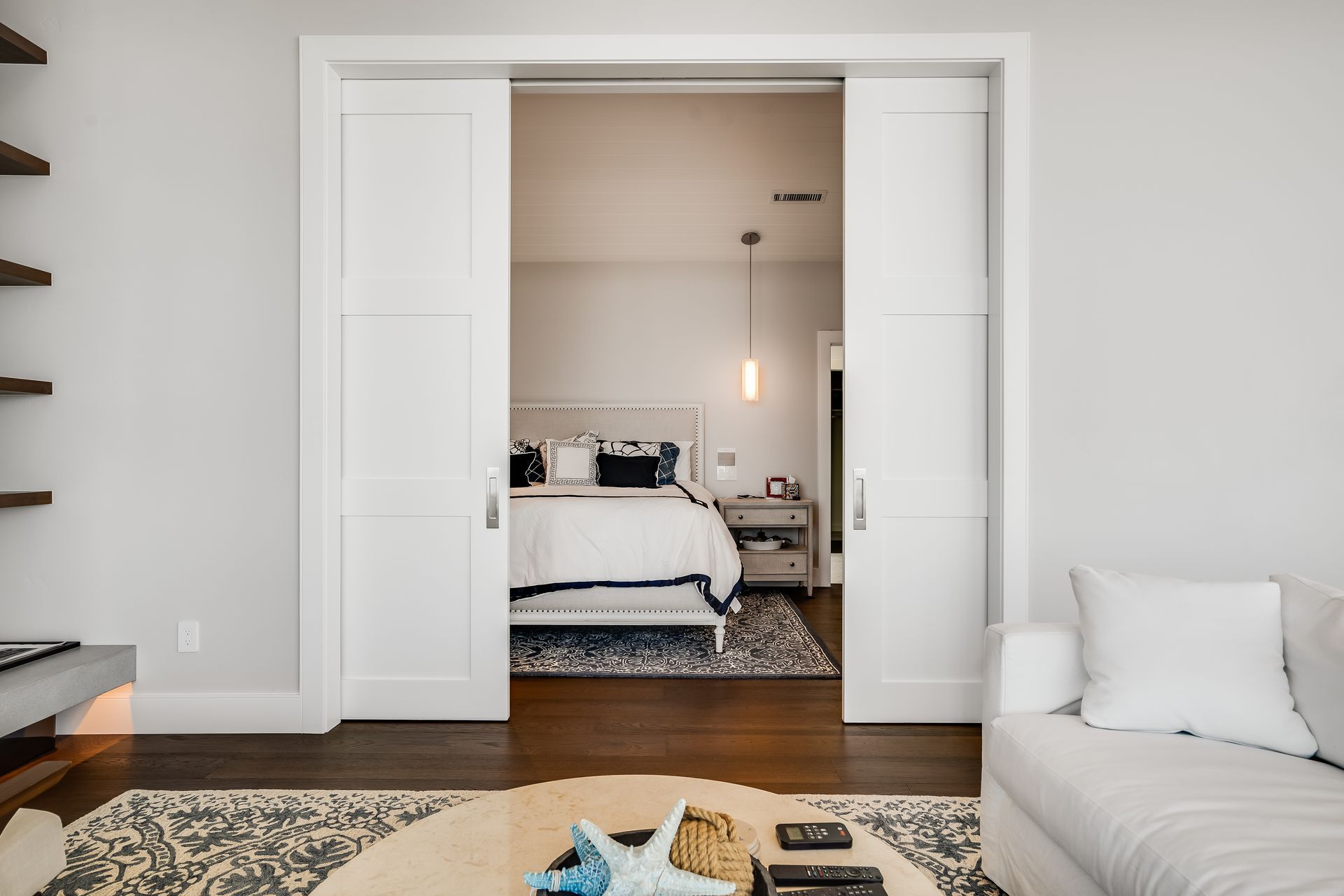 A living room with sliding doors leading to a bedroom