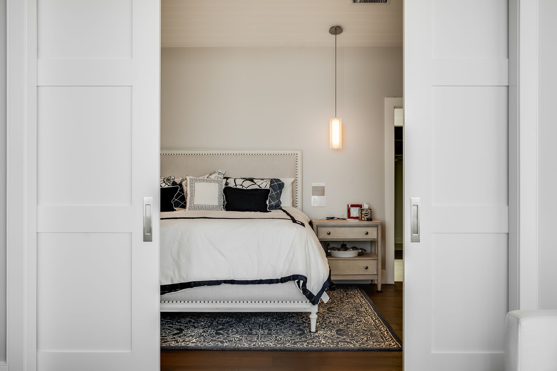 A bedroom with a bed , nightstand , rug and sliding barn doors.