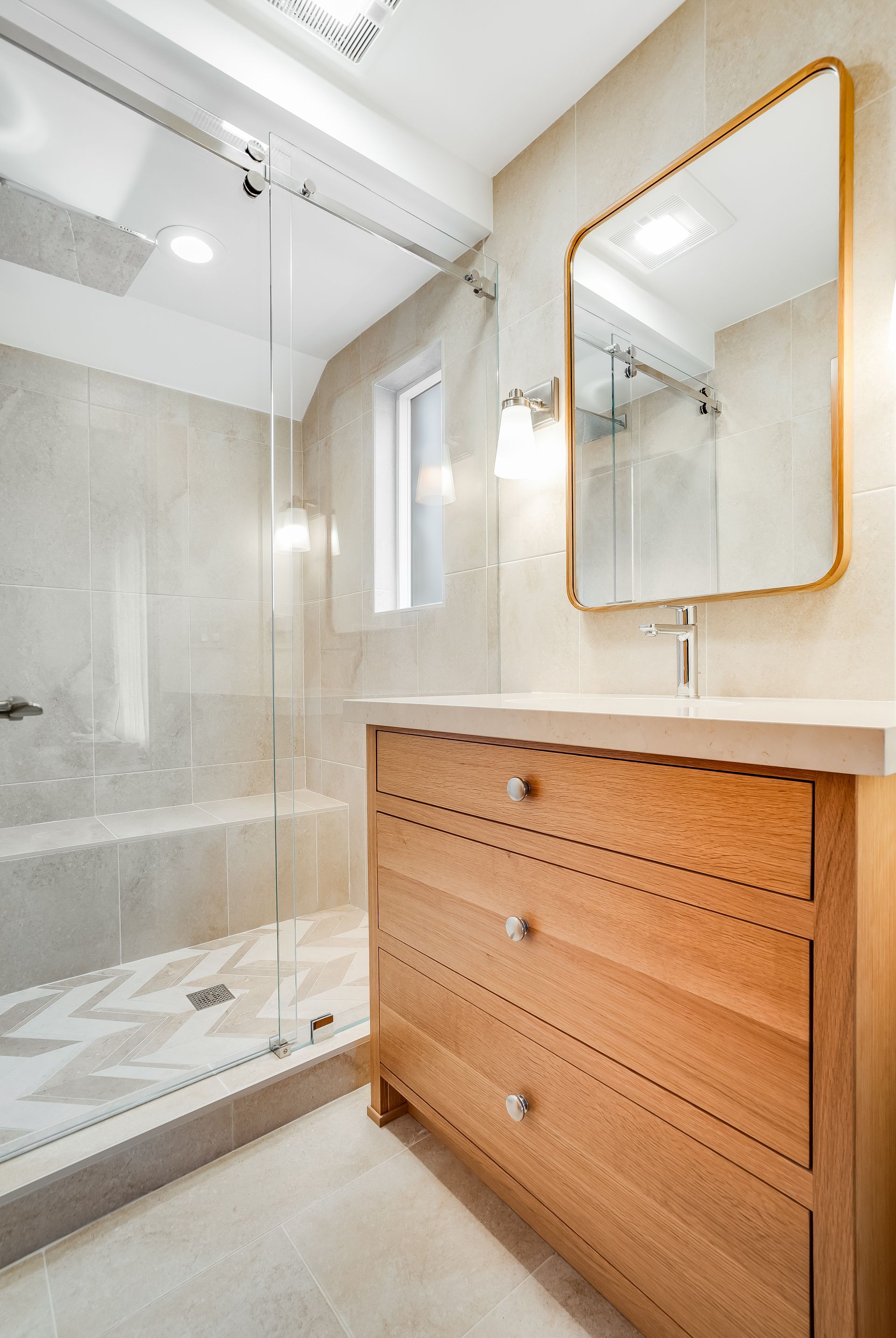 A bathroom with a sink , mirror and walk in shower.