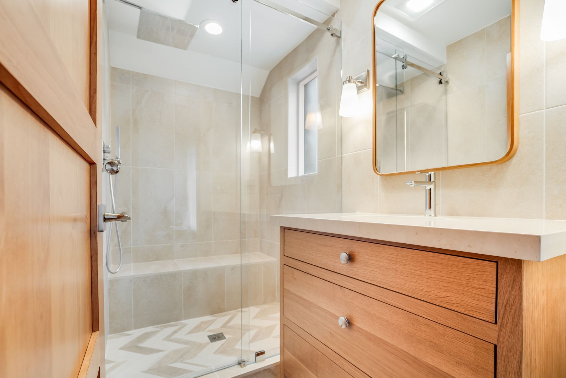 A bathroom with a sink , mirror and walk in shower.