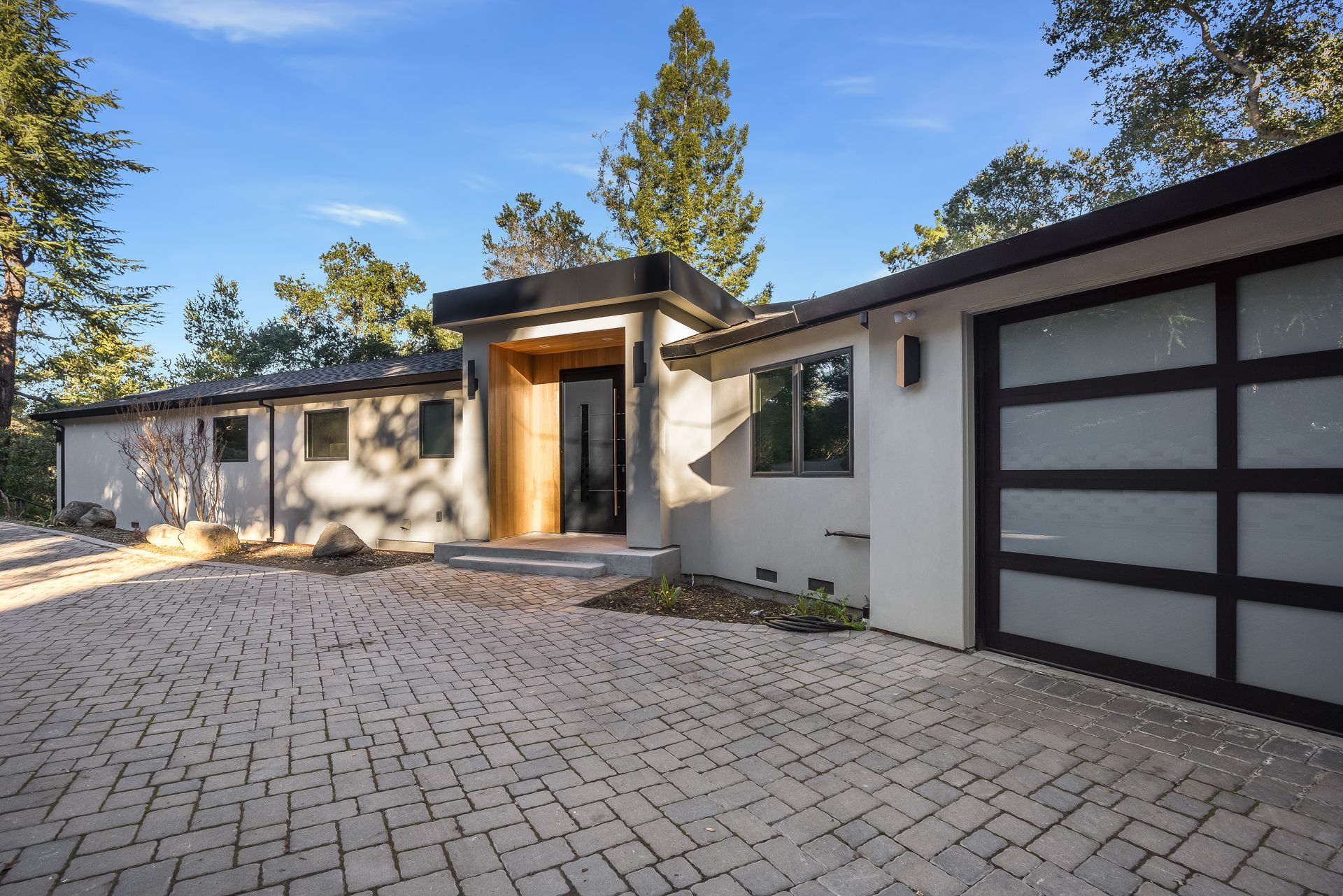 A modern house with a brick driveway and a garage.