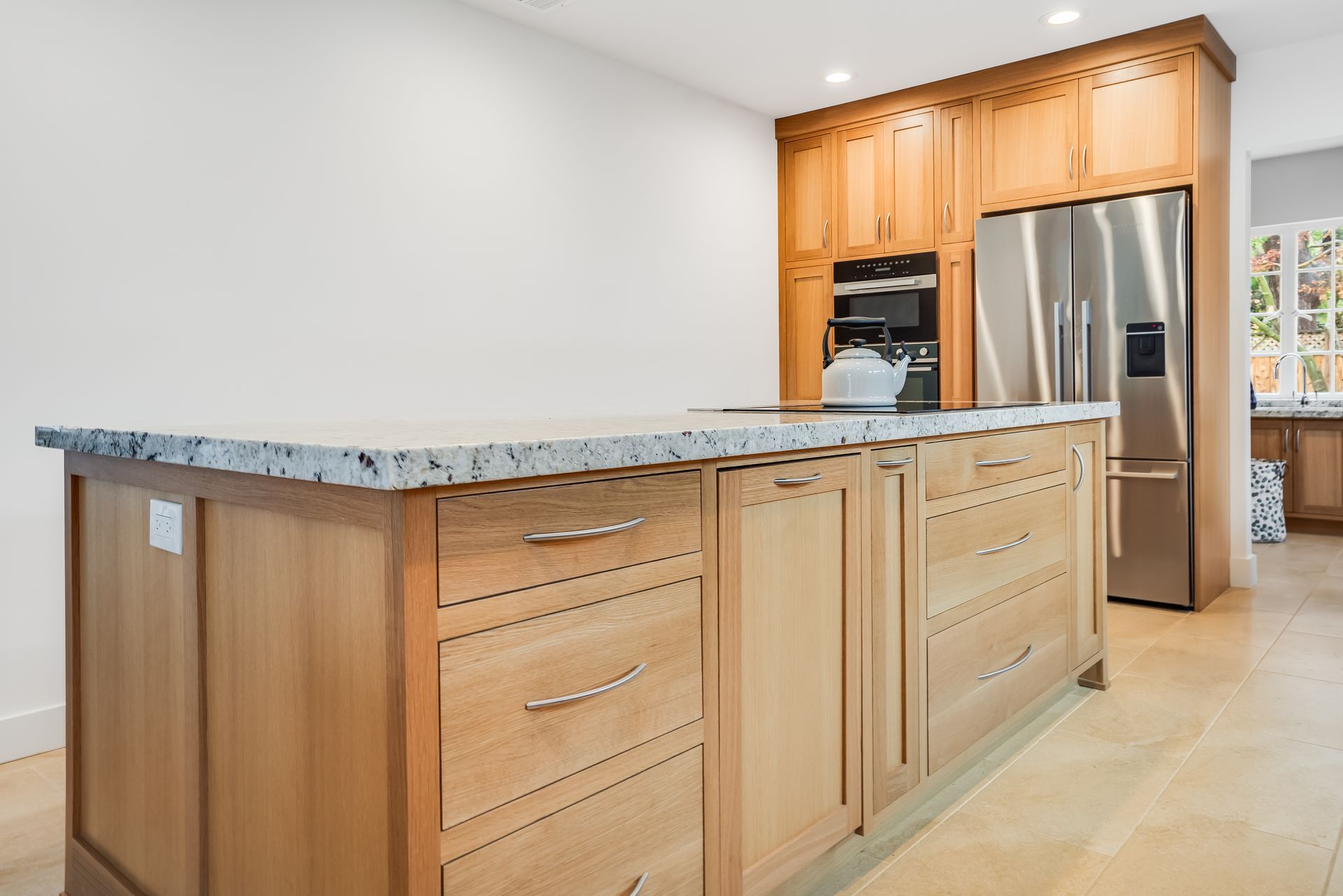 A kitchen with wooden cabinets , stainless steel appliances , and a large island.