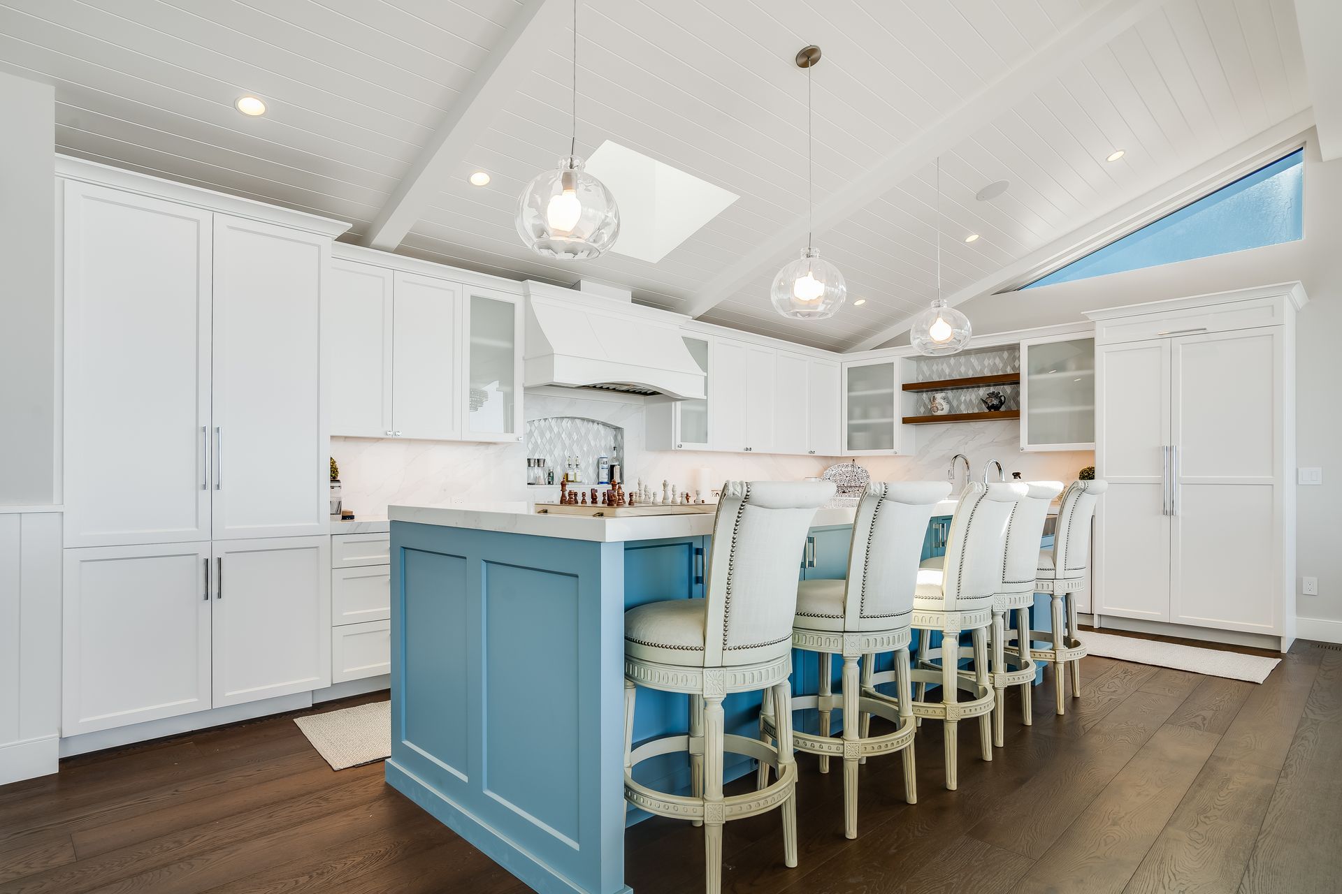 A kitchen with white cabinets and a blue island.