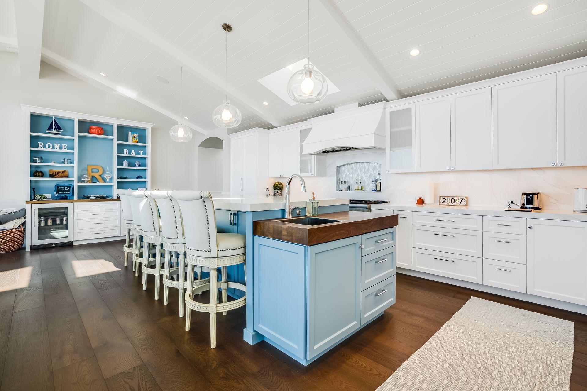 A kitchen with white cabinets and a blue island.
