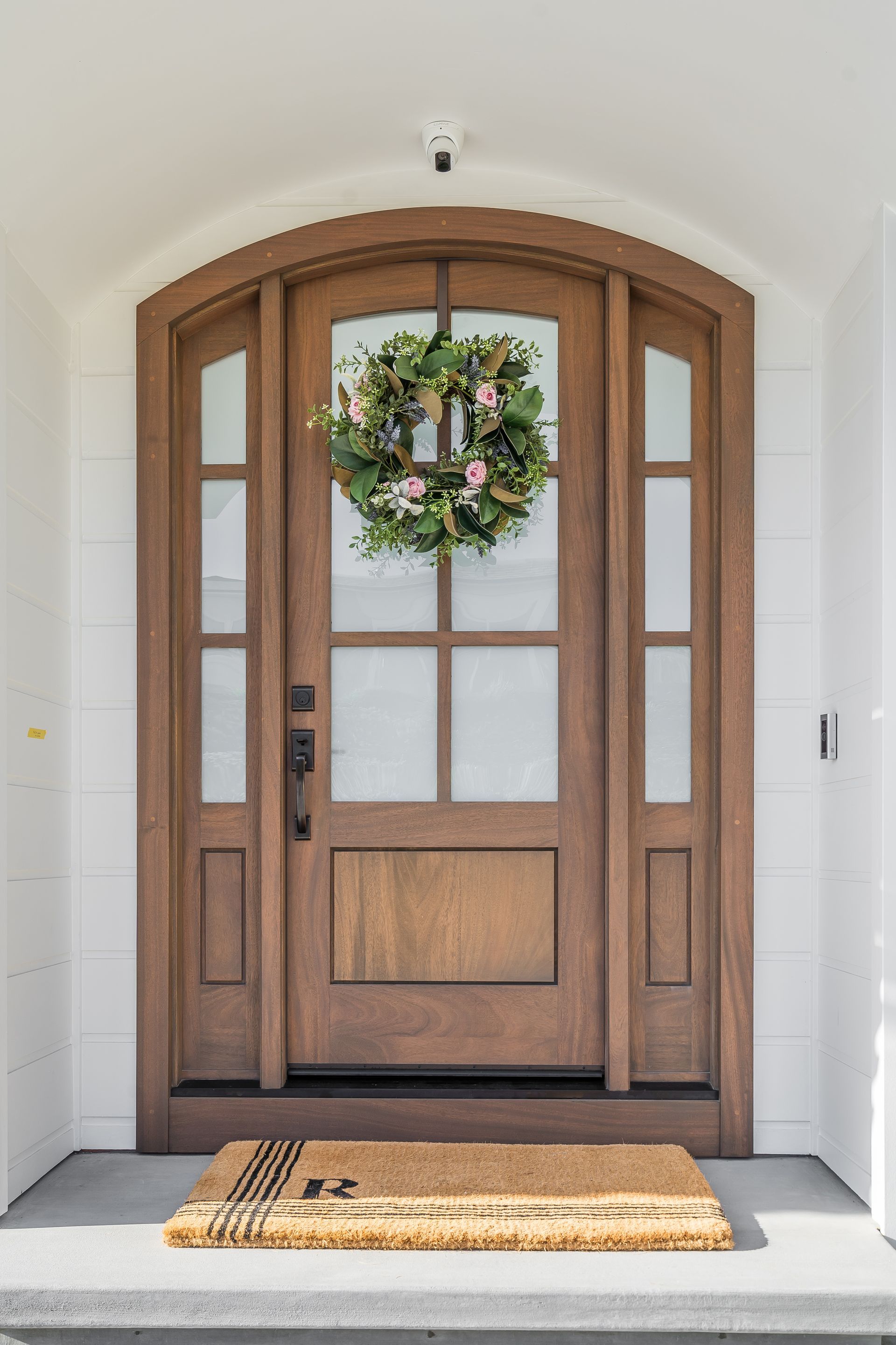 A wooden door with a wreath hanging on it and a door mat.