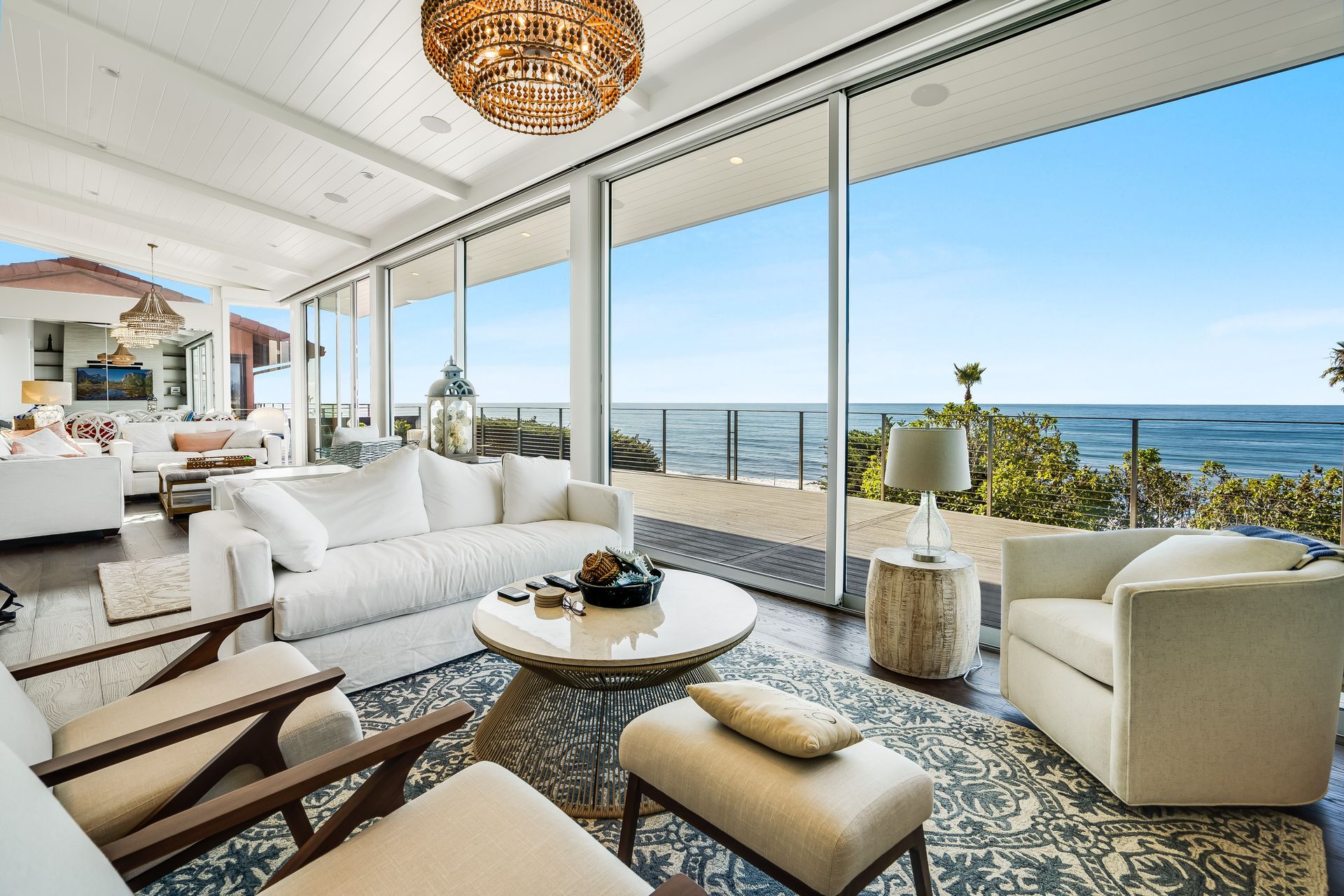 A living room with a couch , chairs and a table with a view of the ocean.