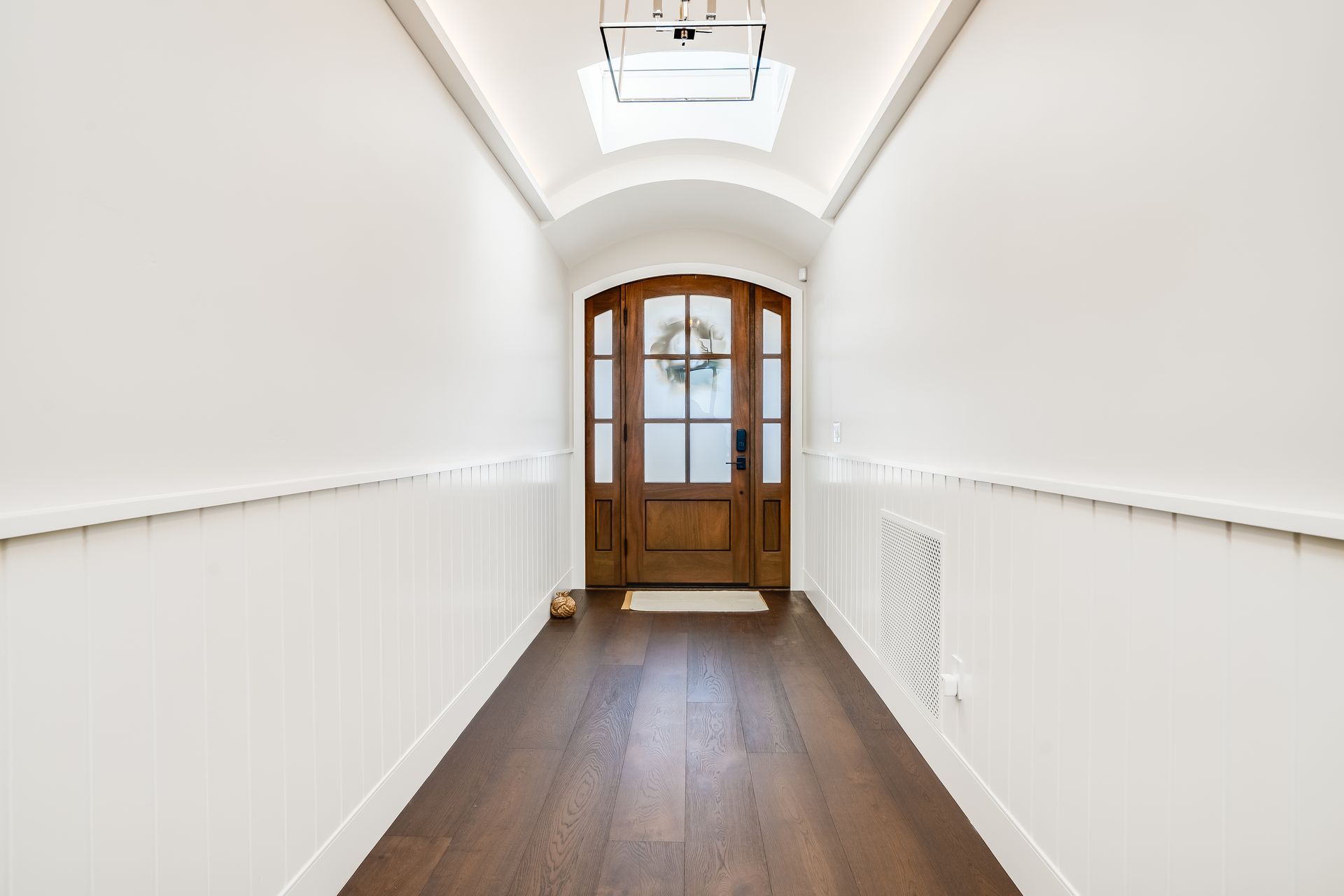 A long hallway with a wooden door and a skylight.