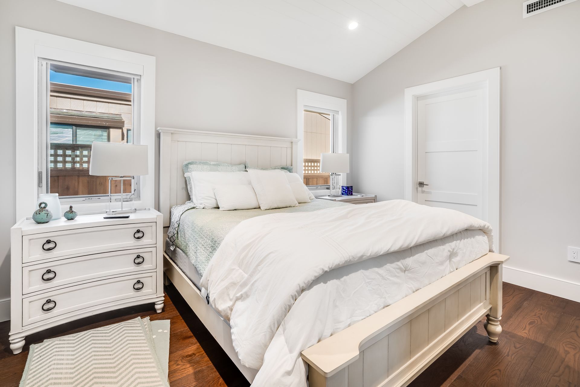 A bedroom with a bed , nightstand , mirror and window.