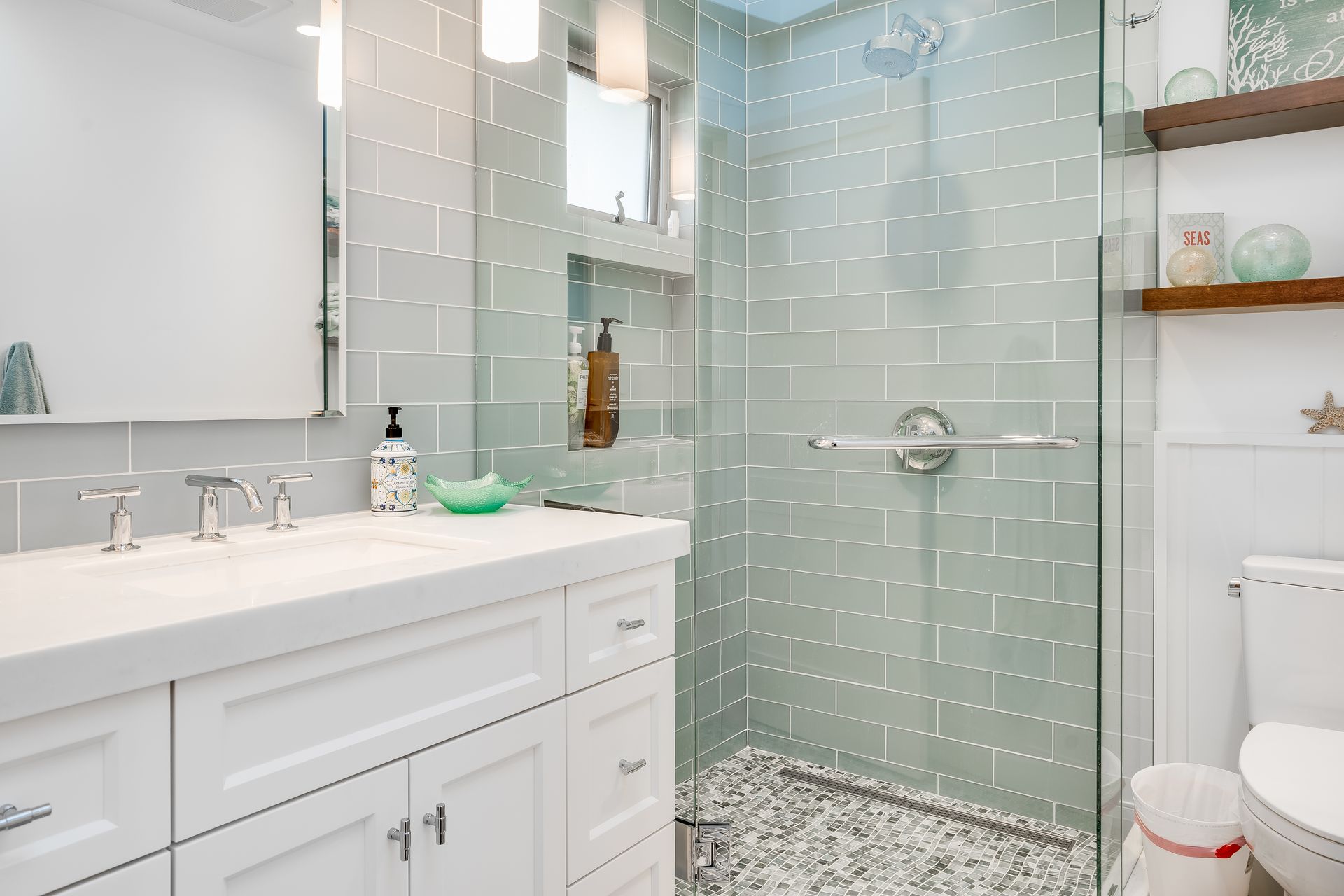A bathroom with a walk in shower , sink , toilet and mirror.