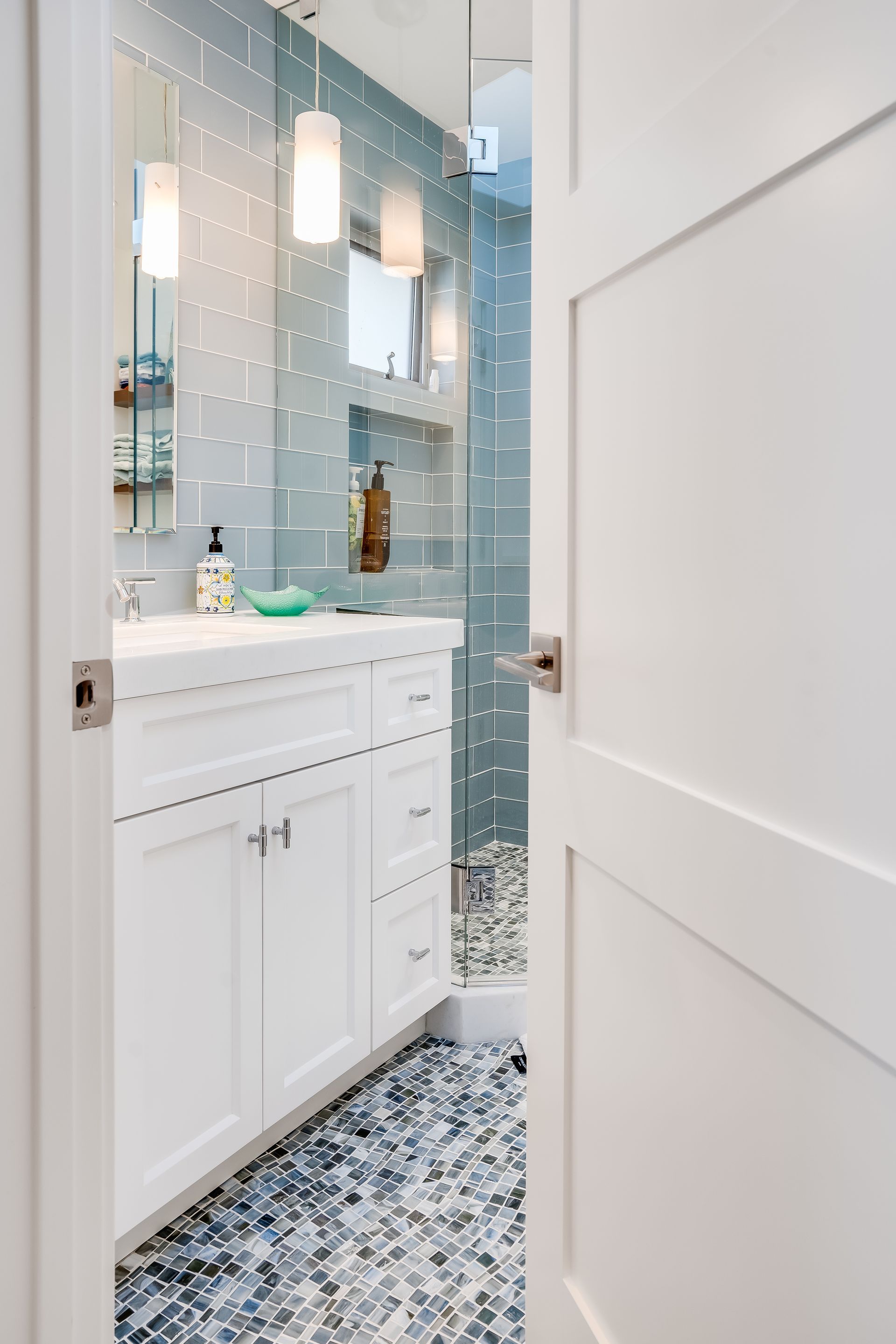 A bathroom with a sink , mirror , and walk in shower.