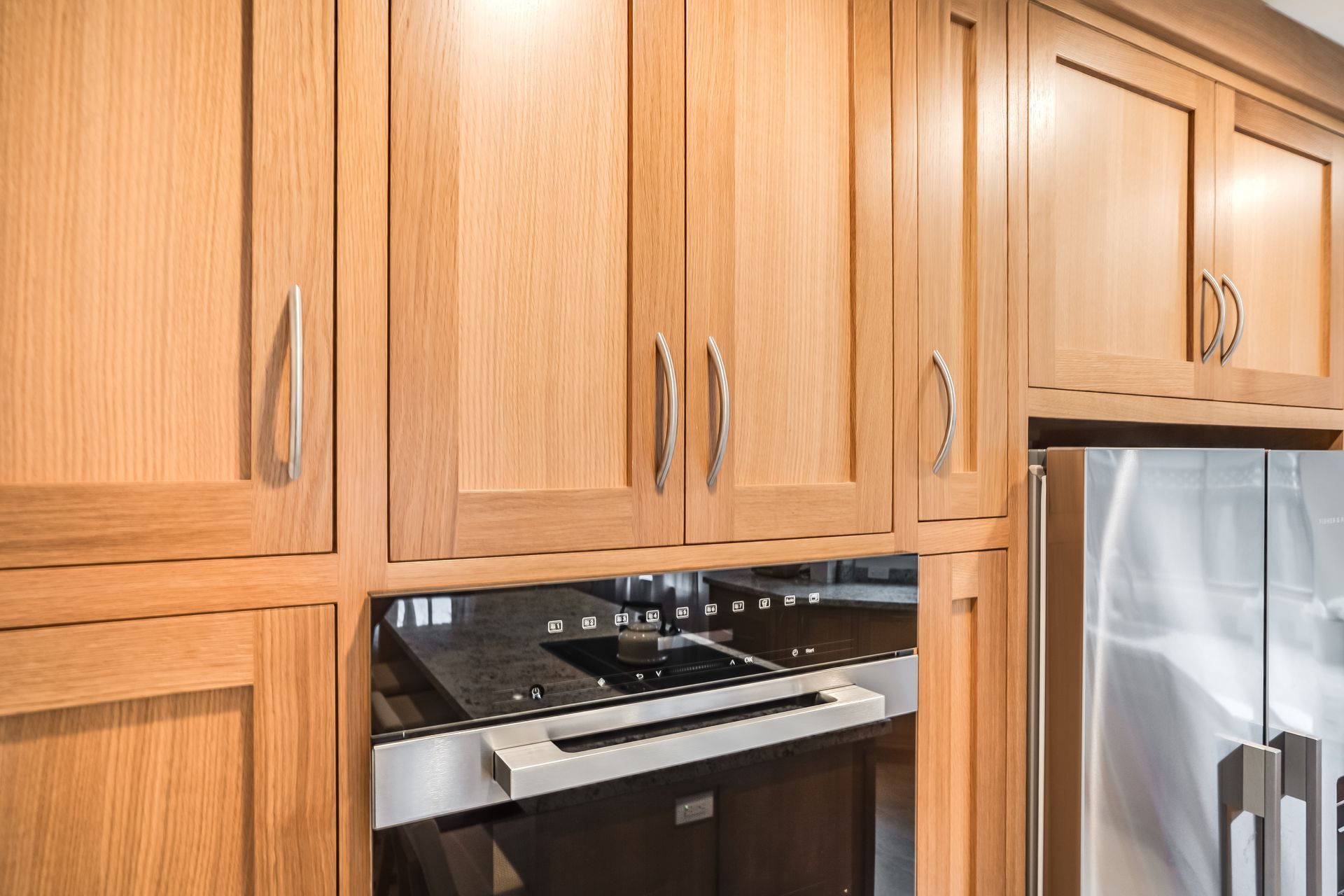 A kitchen with wooden cabinets and a stainless steel refrigerator.