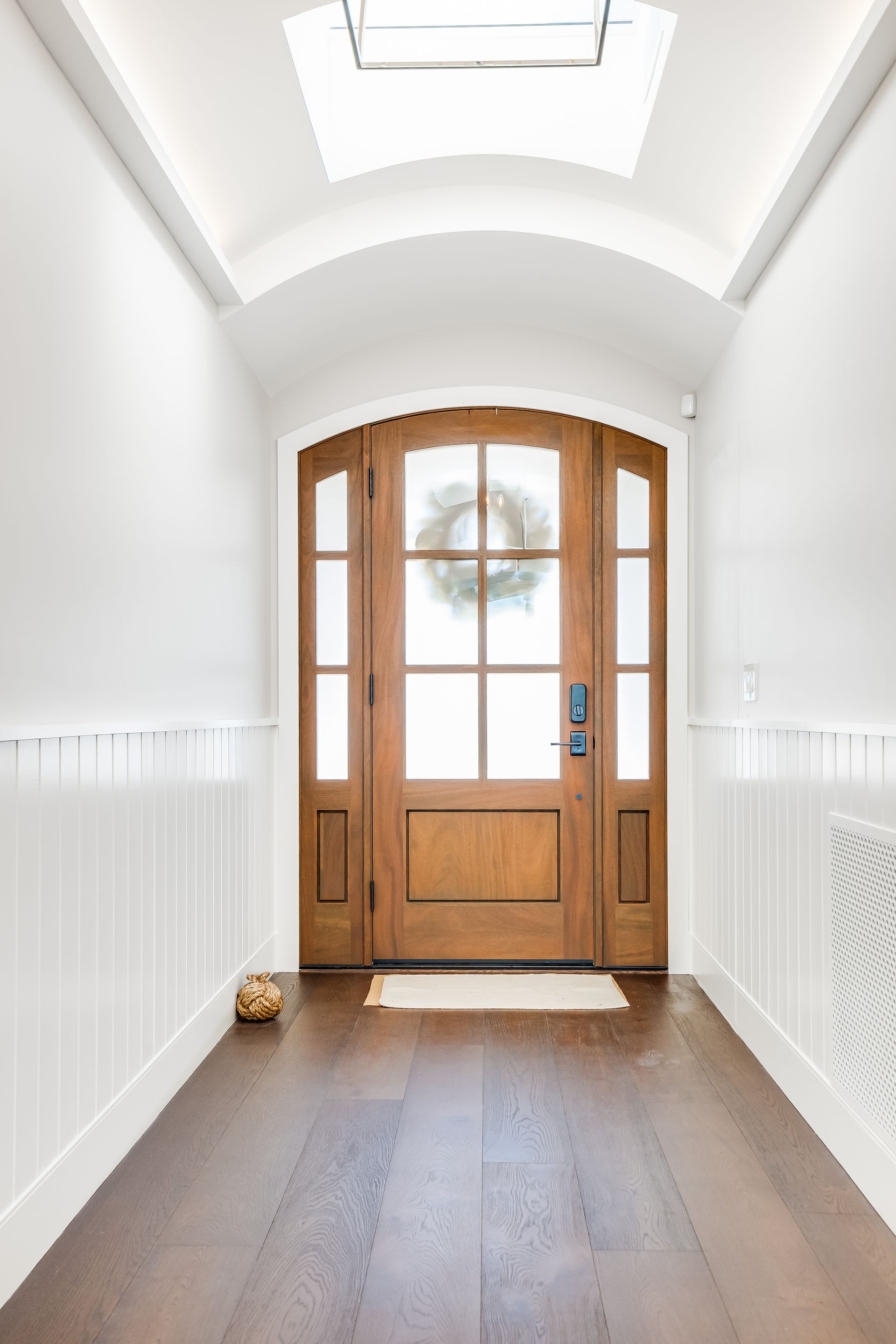 A hallway with a wooden door and a skylight above it.