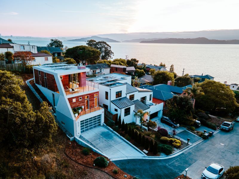 An aerial view of a house on a hill overlooking a body of water.