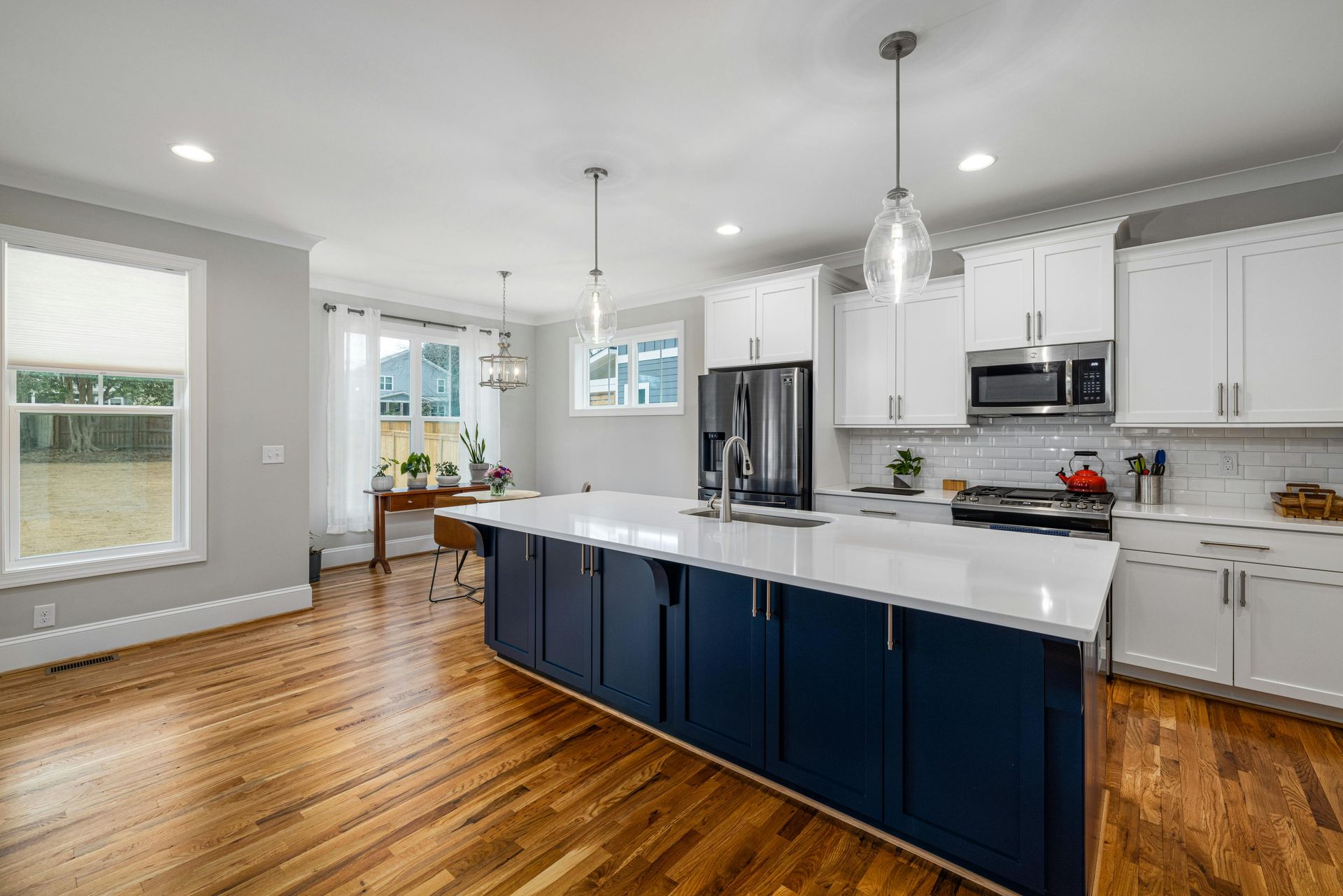 A kitchen with blue cabinets and white cabinets and hardwood floors.
