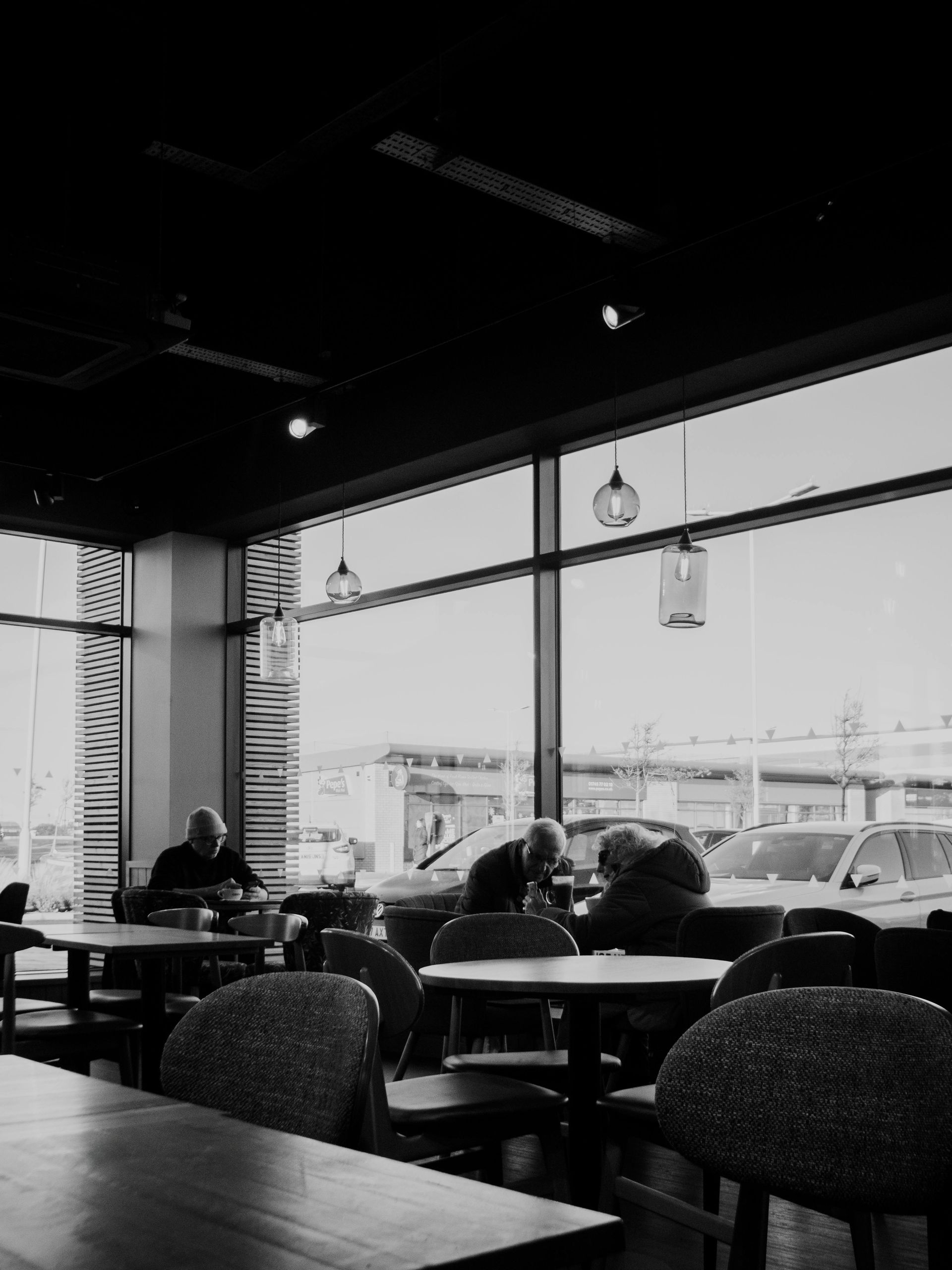 A black and white photo of people sitting at tables in a restaurant