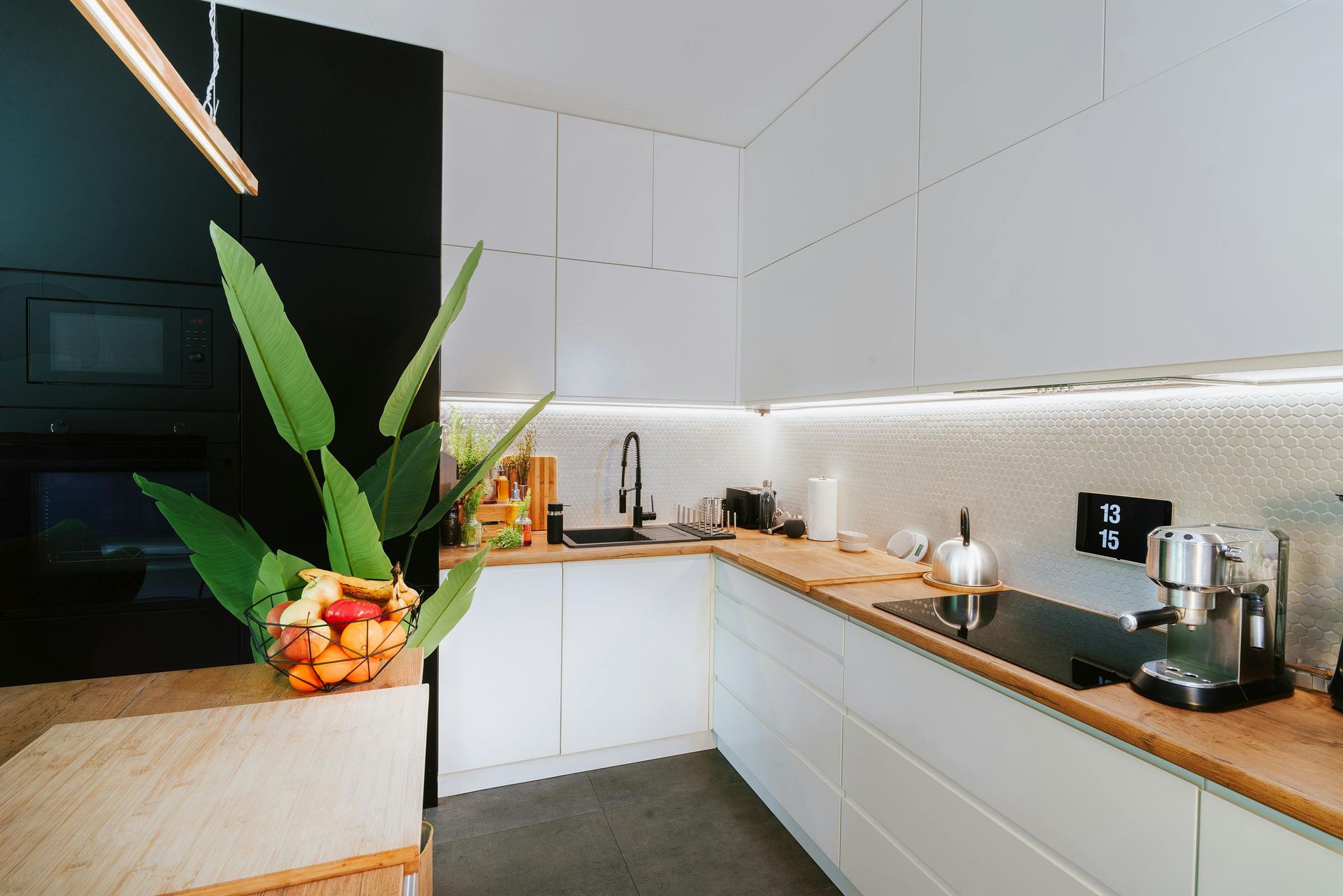A kitchen with white cabinets , wooden counter tops and a stove top oven.