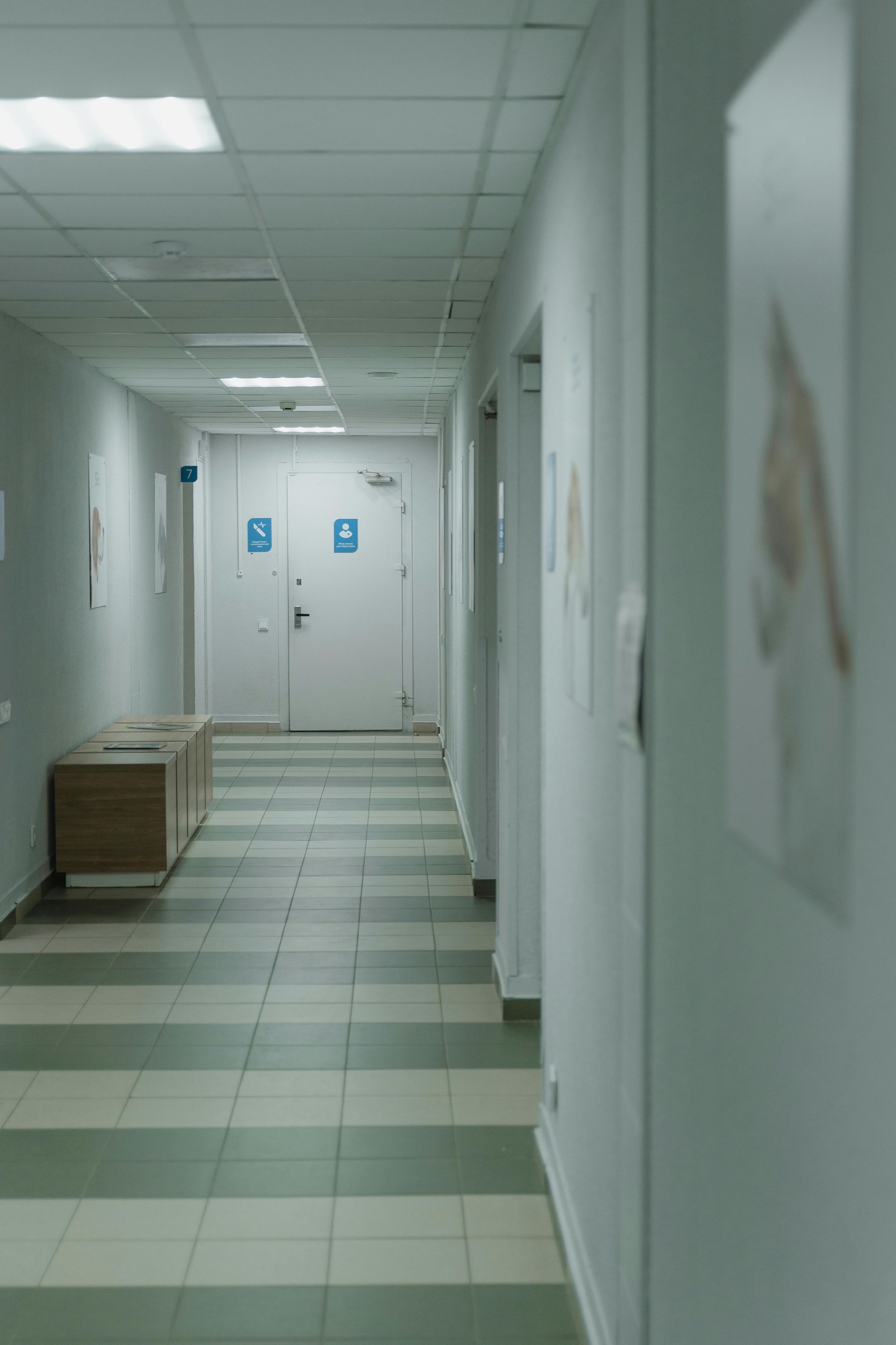 A long hallway in a hospital with a striped floor and a bench.