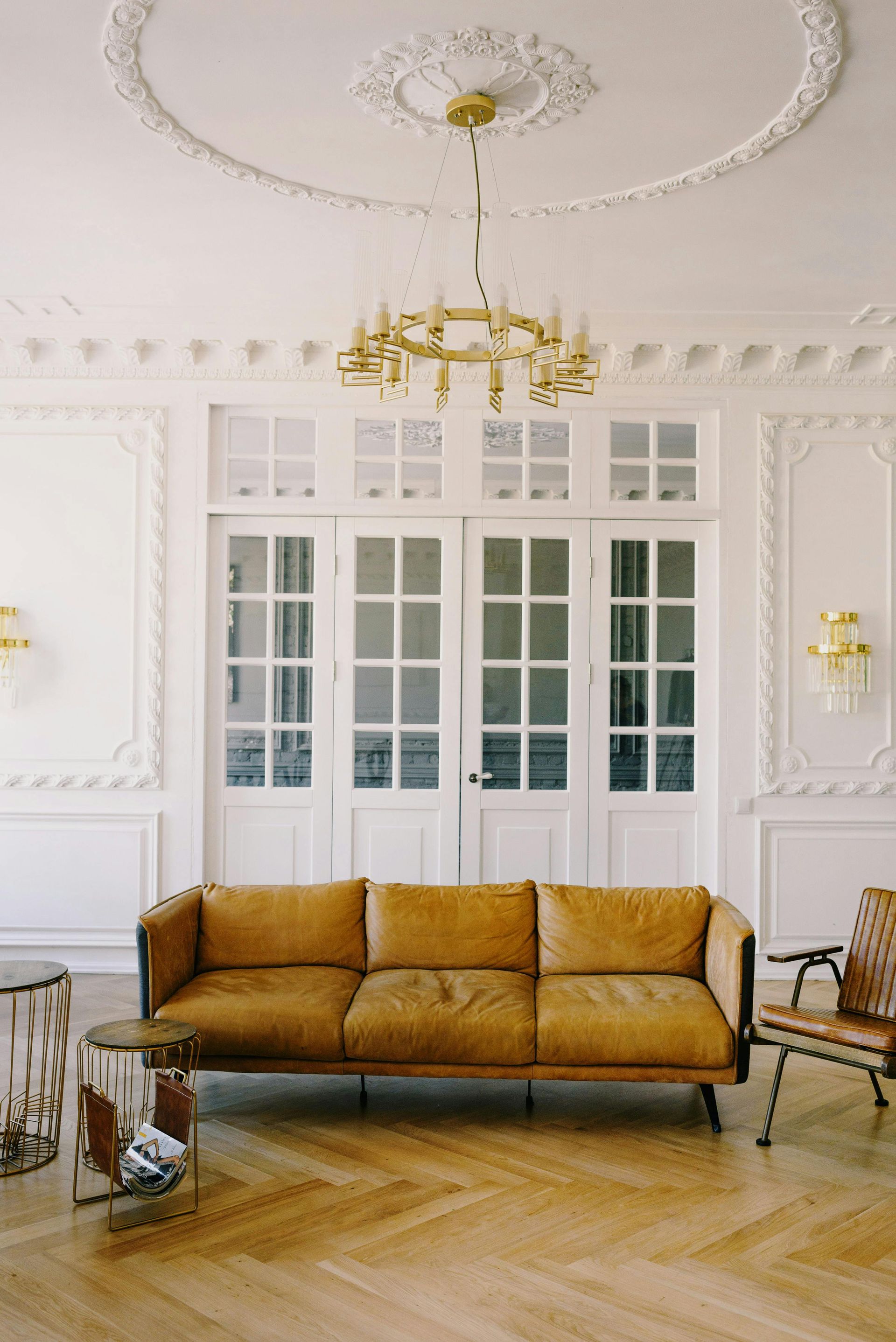 A living room with a couch , chairs , and a chandelier.