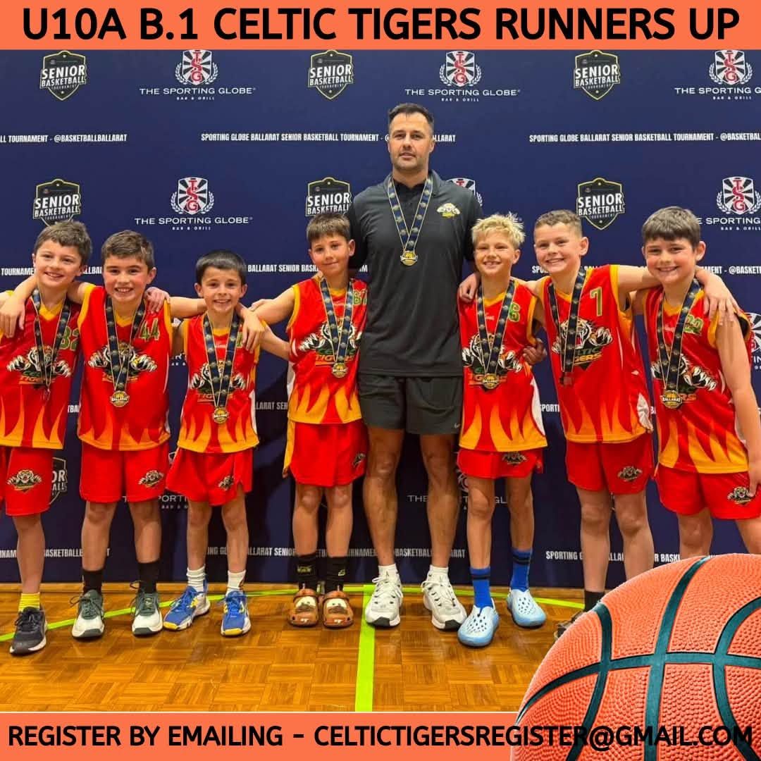 Basketball team and coach posing with runner-up medals in red uniforms on a stage