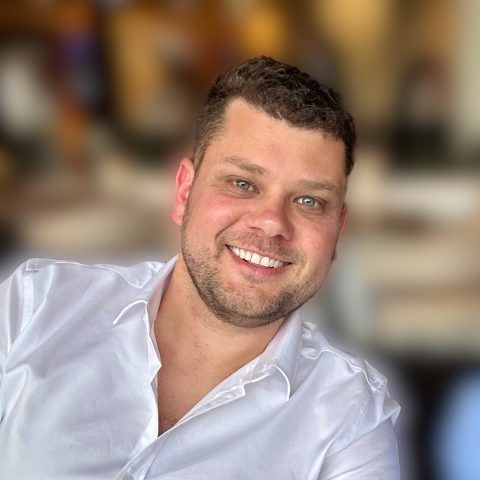 Smiling man in a white shirt with a blurred warm indoor background