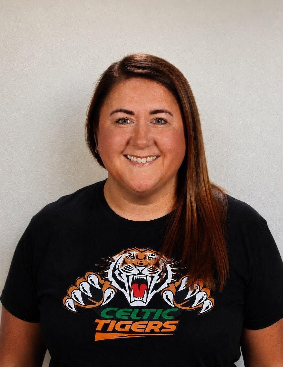 Smiling person in a black Celtic Tigers T-shirt against a light gray background