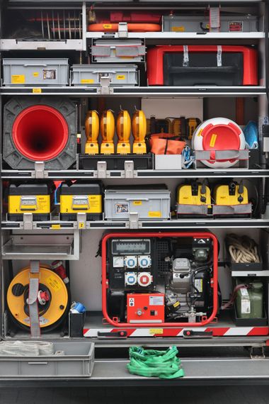 Open truck compartments filled with emergency rescue gear, hoses, tools, and a portable generator