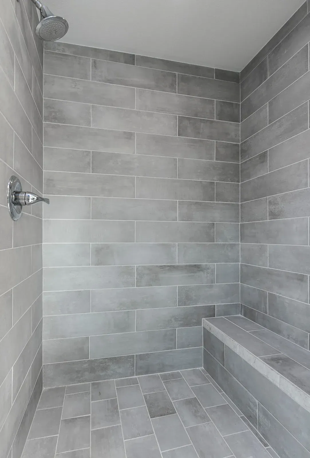 A walk in shower with a bench and a shower head.