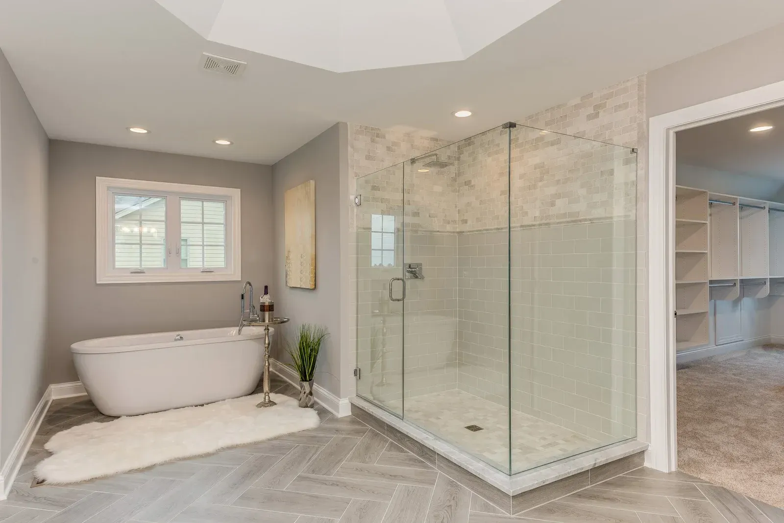 Spacious gray bathroom with a free-standing tub, glass shower, and walk-in closet.