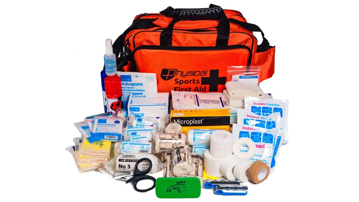 Orange first aid kit bag with assorted medical supplies and bandages laid out in front
