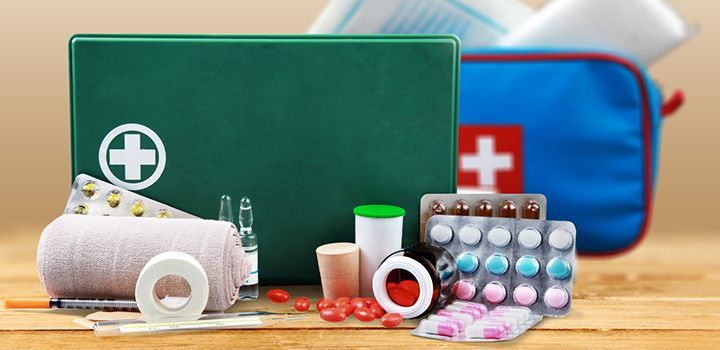First aid kit with pills, bandages, and medicine bottles on a wooden table
