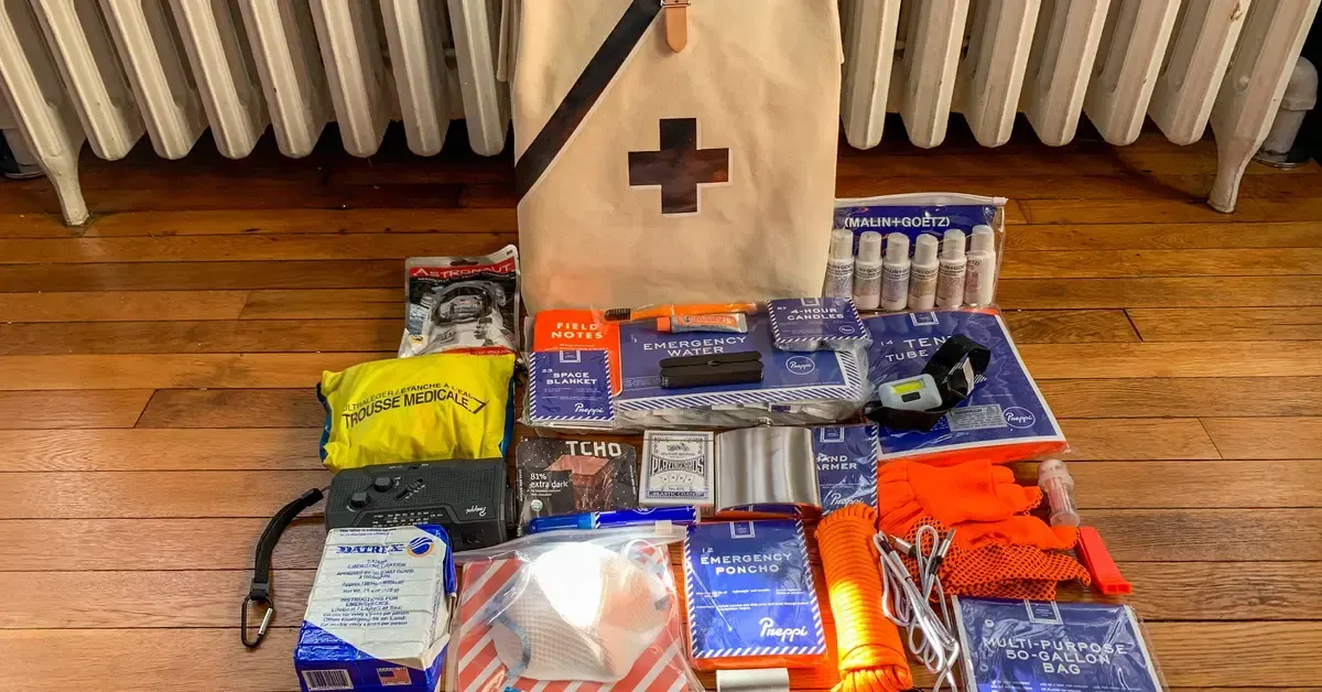 Assorted packaged emergency supplies laid out on a hardwood floor beneath a radiator.