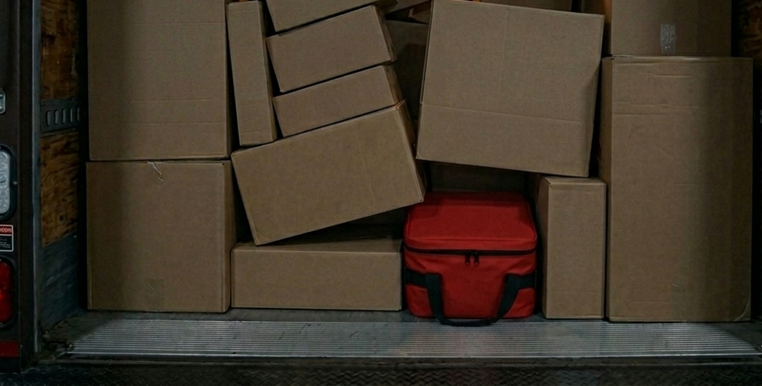 Stacked cardboard boxes with a red bag on the floor in a storage area