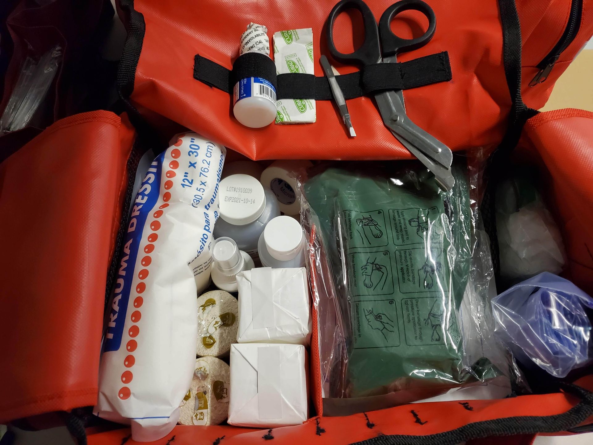 A red bag filled with first aid supplies including scissors