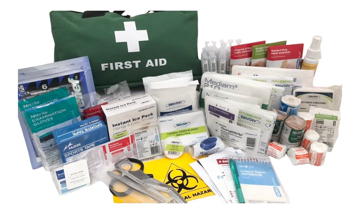 First aid kit with assorted medical supplies, bandages, ointments, gloves, and dressings laid out on a white surface