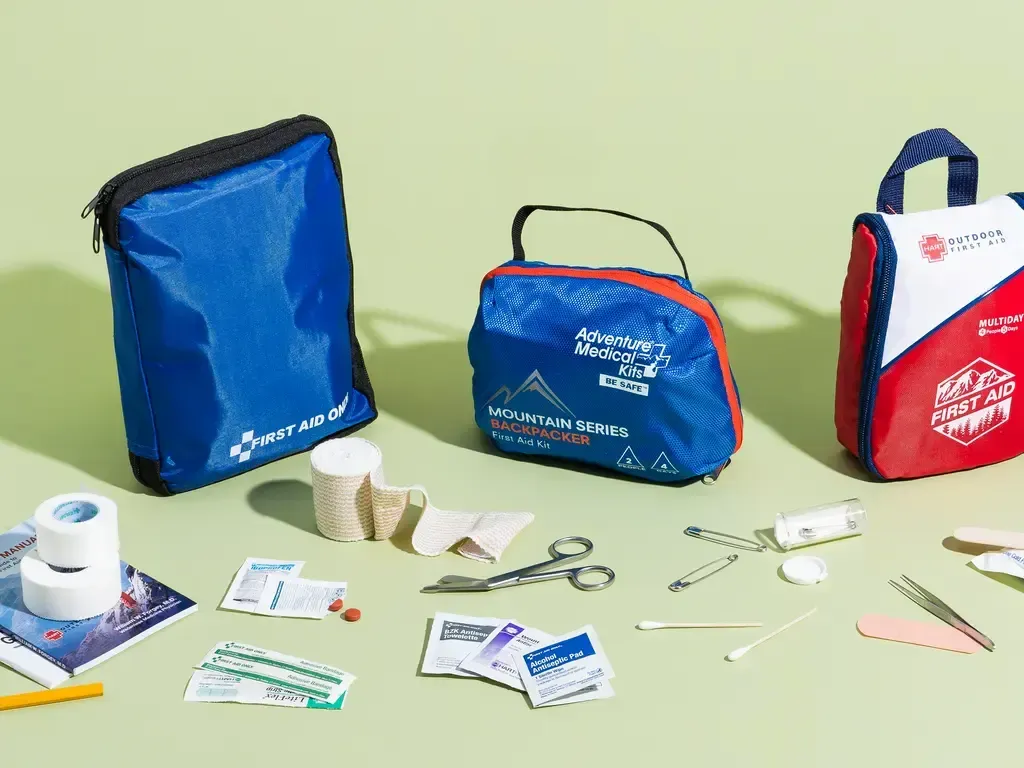 Three blue and red emergency kits with bandages and first-aid supplies laid out on a table.