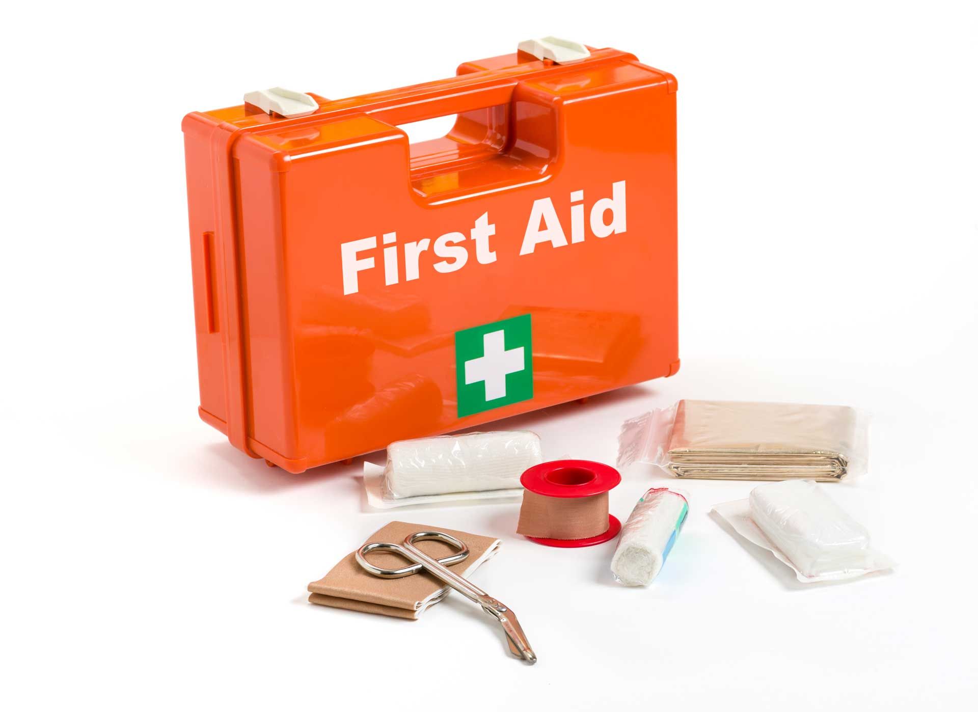 Orange first aid kit with medical supplies scattered beside it