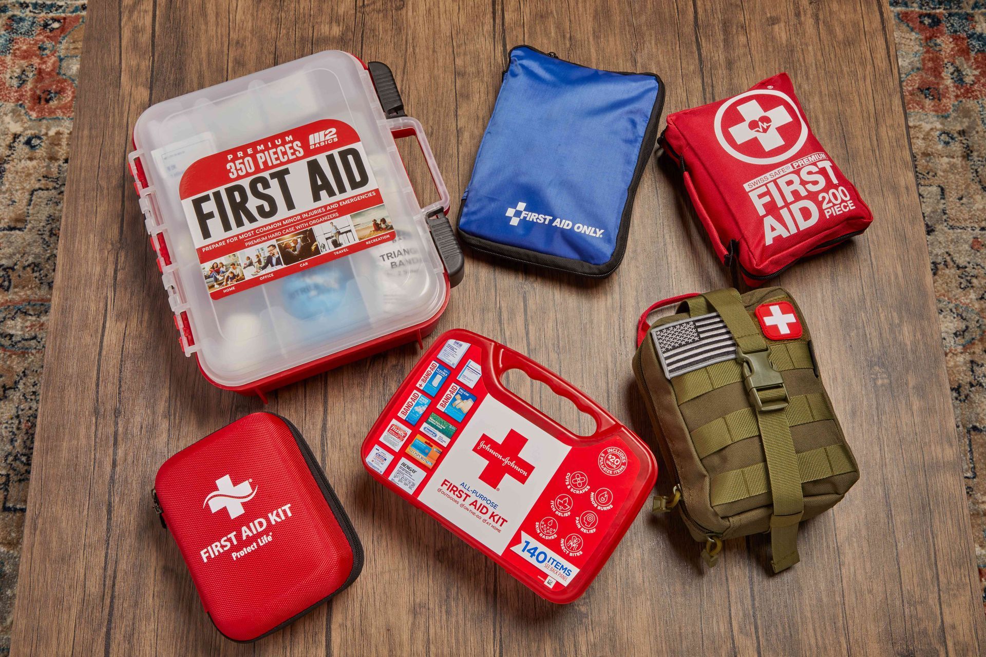 Six first aid kits of various colors arranged on a wooden surface.