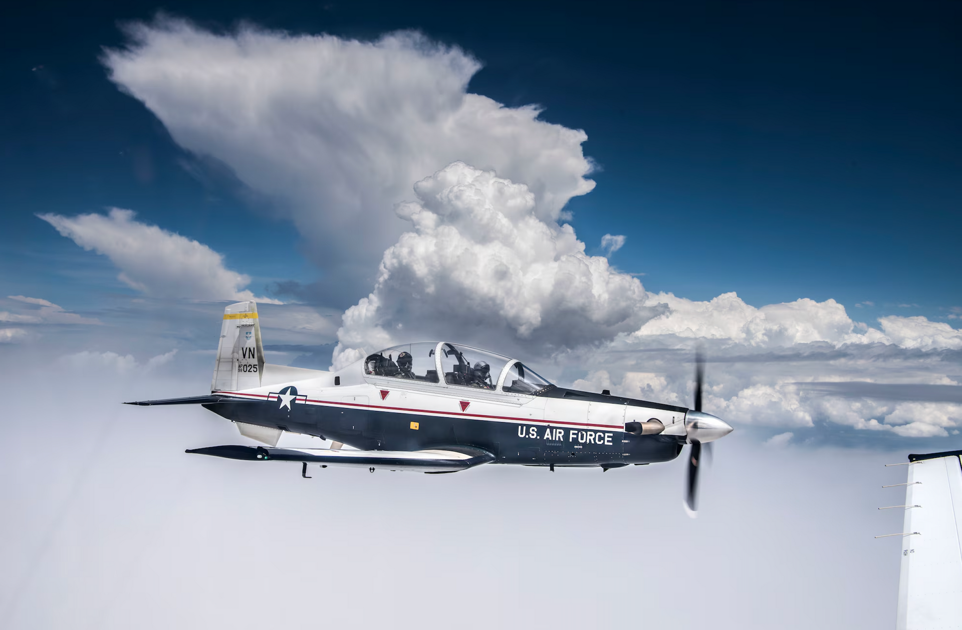 Gray military cargo plane flying in a blue sky, angled upward