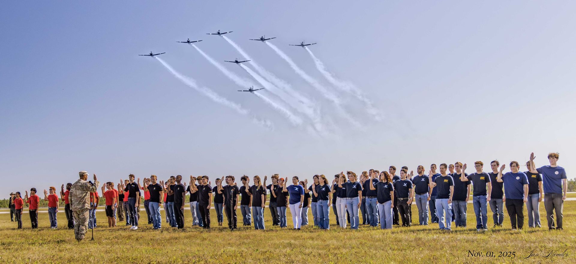 Military recruits take the oath of enlistment as vintage aircraft fly over the Florida air show