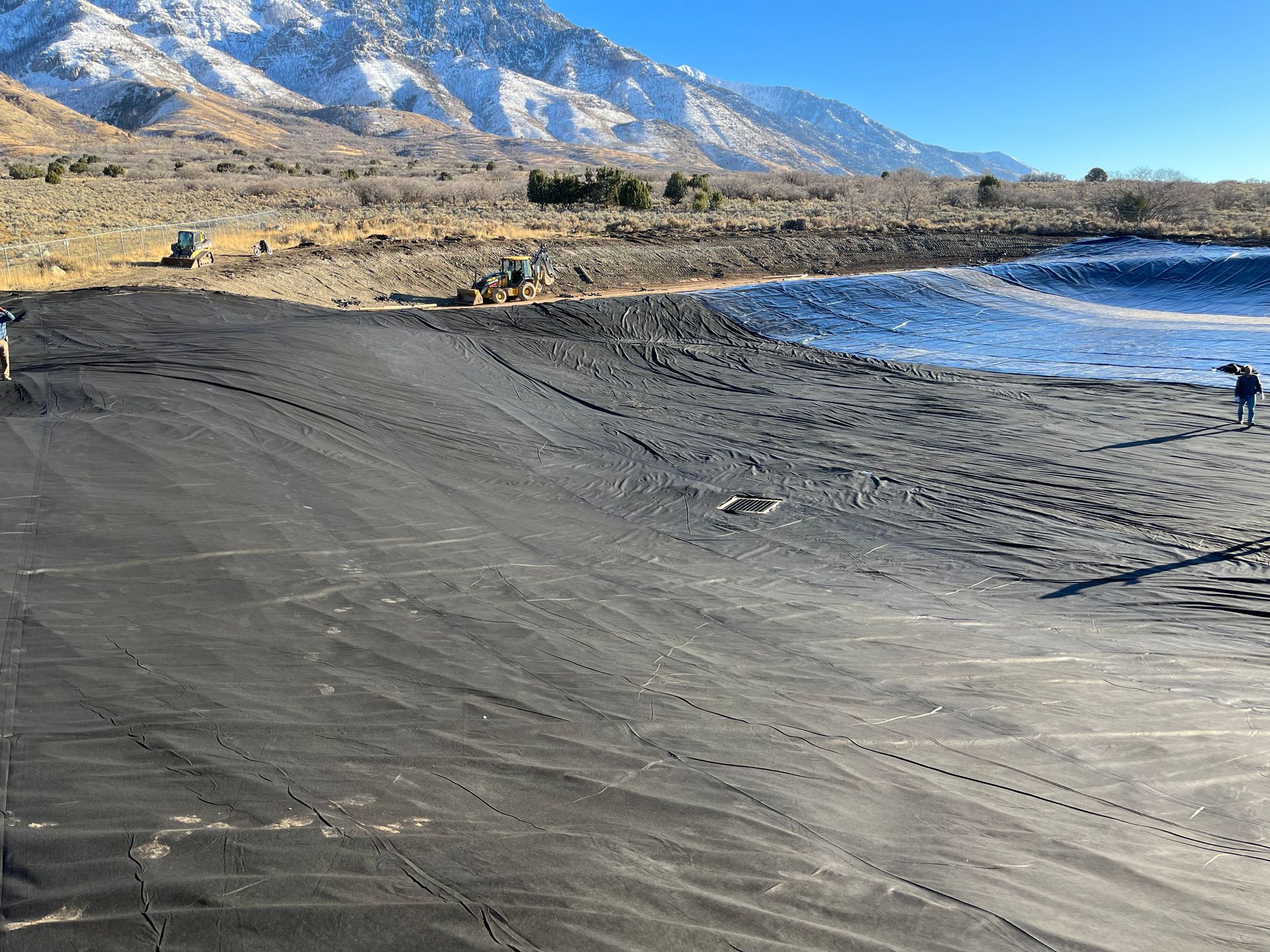 Black sand beach beside blue water with mountains in the background