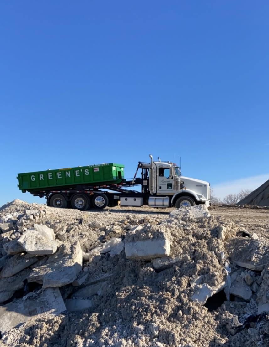 Green dump truck with green container on a debris pile under a blue sky. Green dump truck with green container on a debris pile under a blue sky.