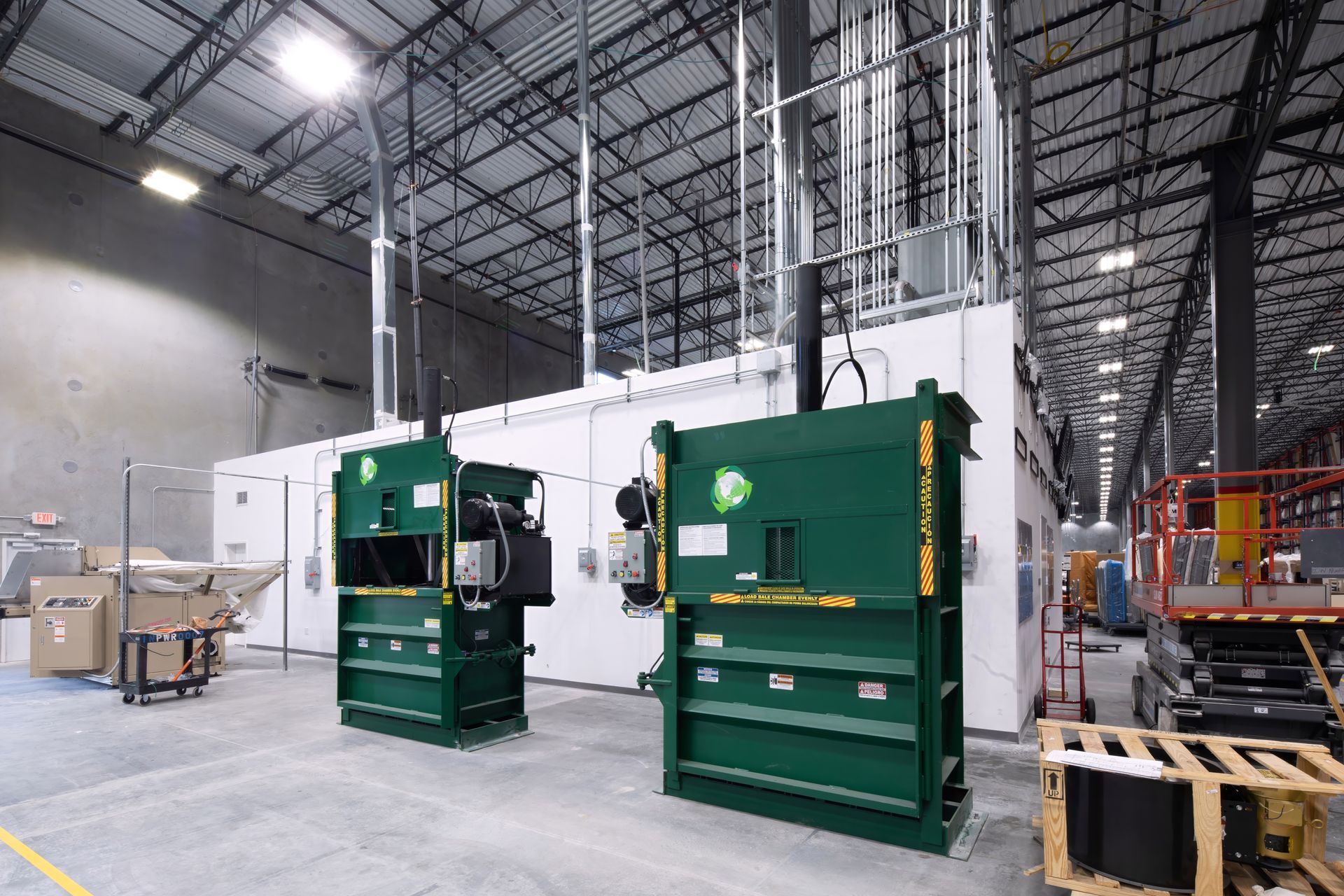 Two green industrial balers in a large warehouse. Two green industrial balers in a large warehouse.