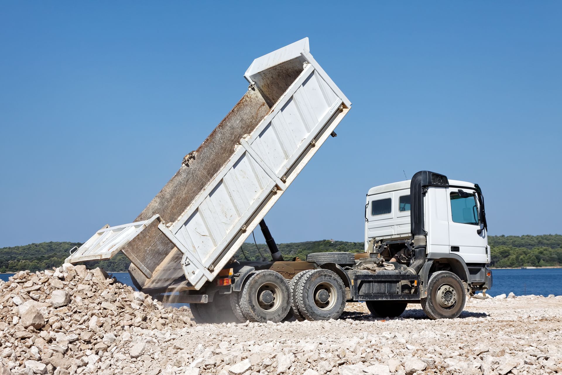 Green dumpster being lifted by a truck in a residential area, containing trash. Green dumpster being lifted by a truck in a residential area, containing trash.