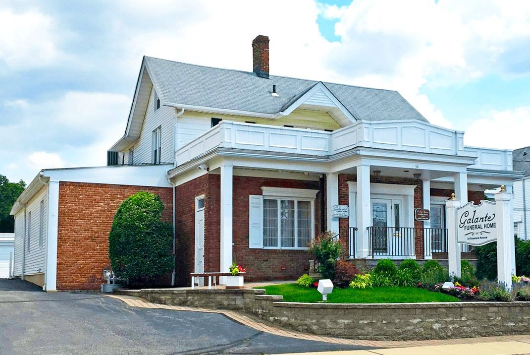 Historic brick-and-white house with porch and landscaped front yard