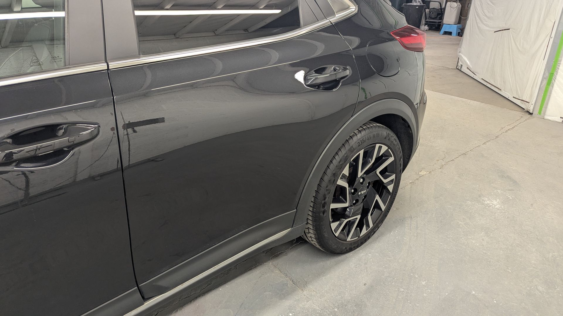 Dark gray SUV parked indoors, showing the side and rear wheel in a garage.