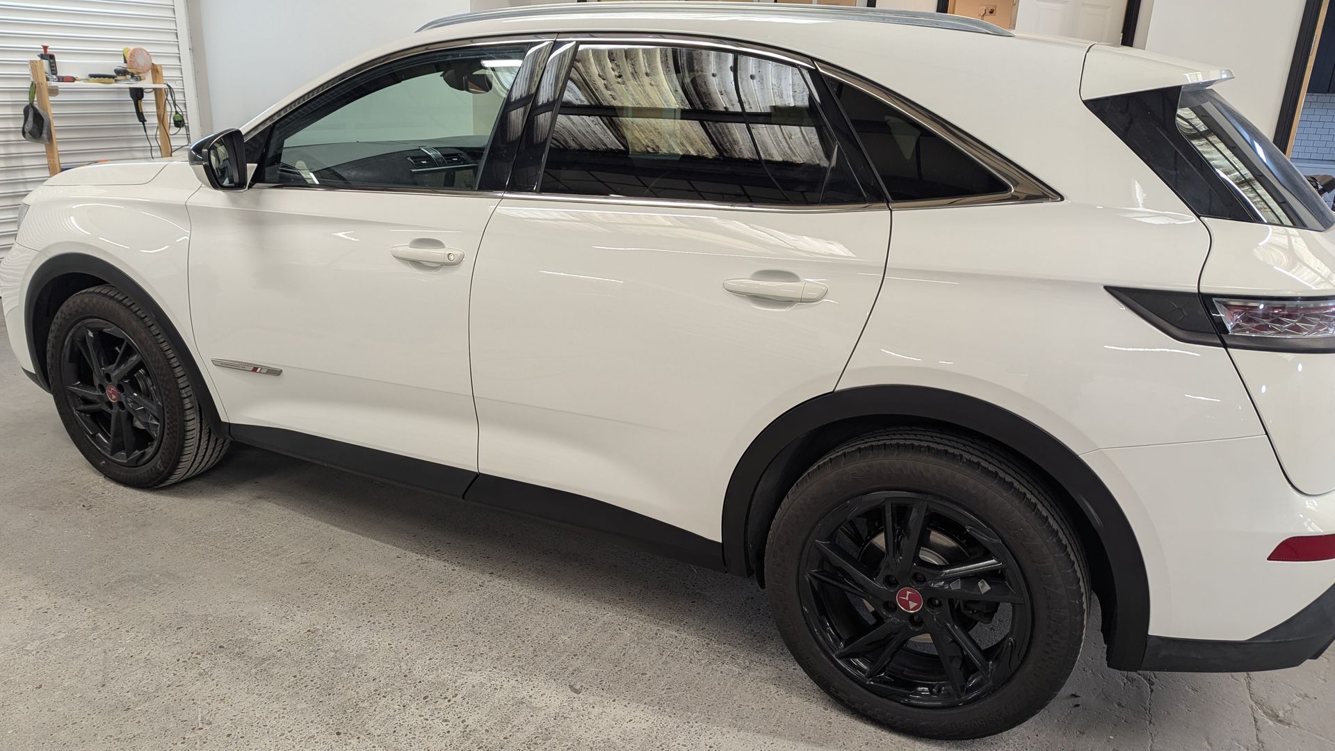 White SUV with black rims parked in an indoor garage or showroom.