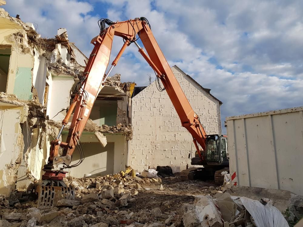 A Large Orange Excavator is Demolishing a Building — Husky Demolition In Waratah, NSW