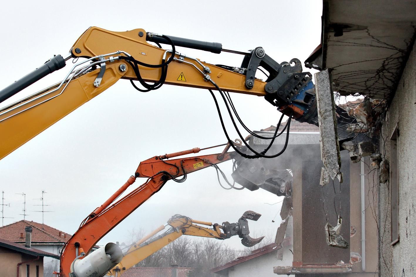A Yellow and Orange Excavator is Demolishing a Building — Husky Demolition In Kurri Kurri, NSW